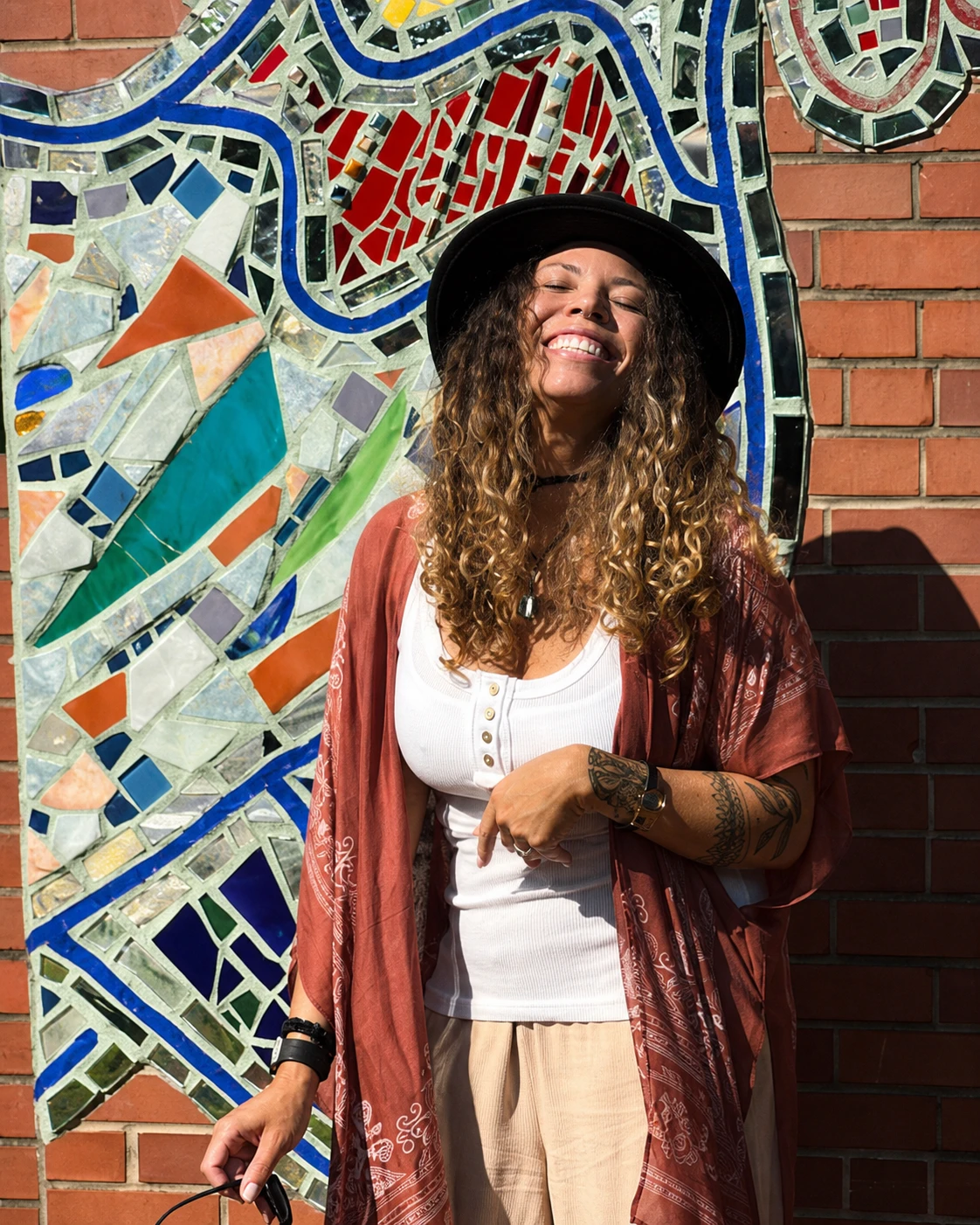 The host of The Sacred Guesthouse smiling in front of a colorful mosaic