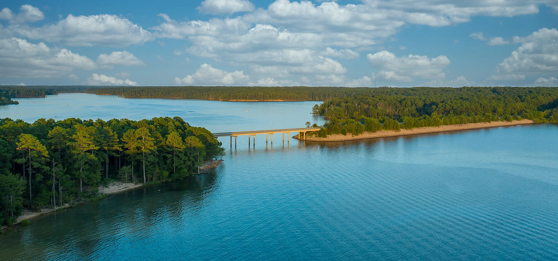 A wide view over a lake surrounded by green forest